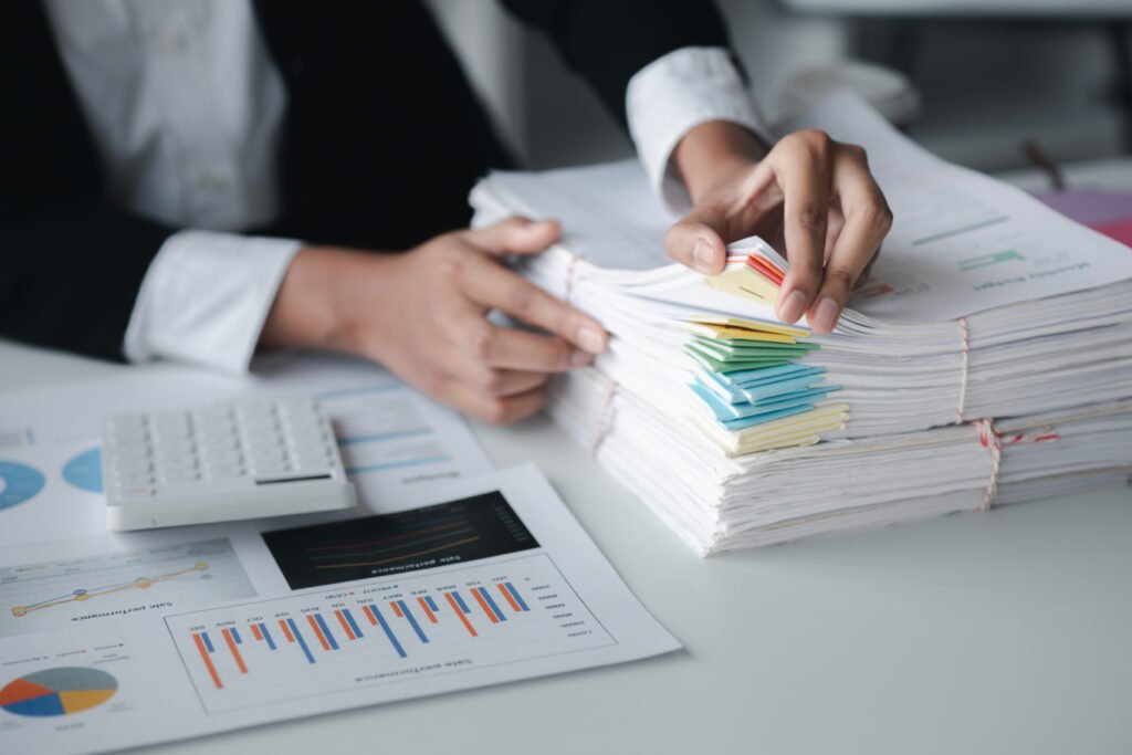 Businessman Looking Through Stacks Of Papers On De RRG587R 1 1024x683